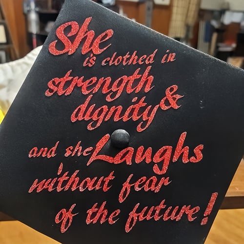 Graduation Cap that says "She is clothed in strength and dignity and she laughs without fear of the future!"